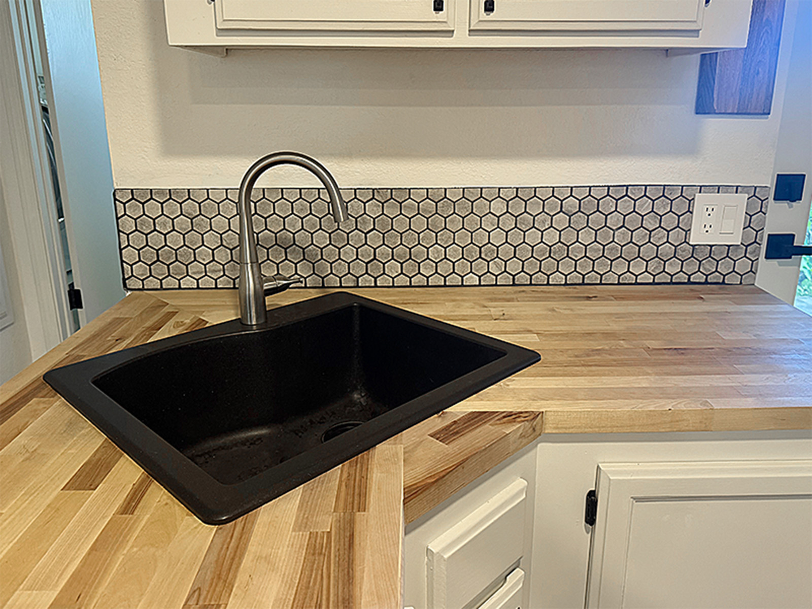 Kitchen renovation featuring drop-in sink installation with plumbing hookup, high-arc standard faucet, and custom hexagonal tile backsplash with professional grouting.