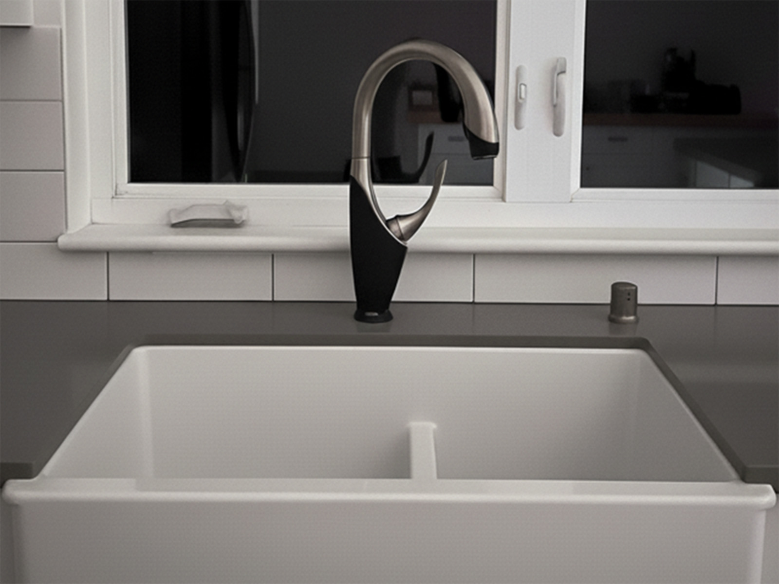 Kitchen renovation featuring new cabinet installation with modern hardware, farmhouse-style sink with full plumbing hookup, and pull-down faucet with integrated soap dispenser